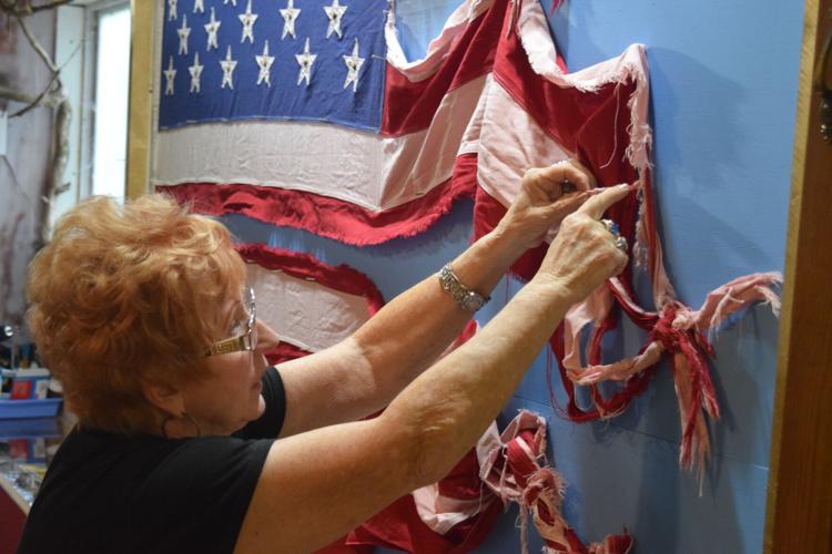 Harriett McFeely, owner of the Bigfoot Crossroads of America Museum in Hastings, Tuesday points out a tiny braid discovered among the unexplained knots and braids found in a flag from Garrison.
