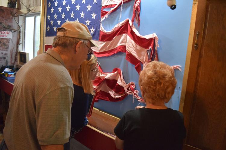 Harriett McFeely (right), owner of the Bigfoot Crossroads of America Museum in Hastings, Tuesday points to unexplained knots and braids found in a flag from Garrison to Jim Daro of Garrison (left) and Margo Hlavac of Garrison.