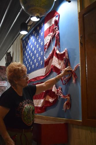 Harriett McFeely, owner of the Bigfoot Crossroads of America Museum in Hastings, Tuesday points out unexplained knots and braids found in a flag from Garrison.